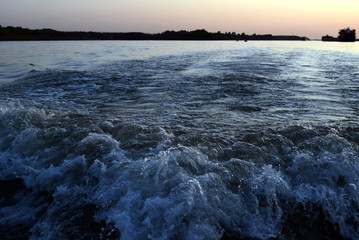 wave from a boat at sunset