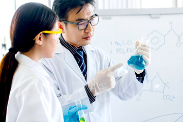 Fototapeta premium Two scientists are working in laboratory. Young female researcher and her senior supervisor are doing investigations with test tubes.