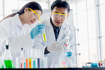 Two scientists are working in laboratory. Young female researcher and her senior supervisor are doing investigations with test tubes.