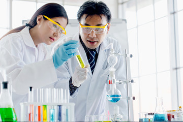 Two scientists are working in laboratory. Young female researcher and her senior supervisor are doing investigations with test tubes.