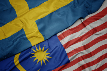 waving colorful flag of malaysia and national flag of sweden.