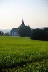 Fototapeta na wymiar Kirche und Wiese in Sommer Landschaft