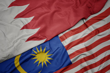 waving colorful flag of malaysia and national flag of bahrain.