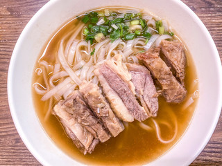 bowl of Chinese food meat noodles on table