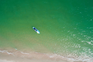 Young woman paddling on SUP board on the tropical beach. Active summer vacations with paddle board.