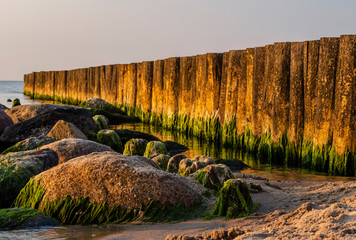 Evening seascape with a breakwater and stones with algae