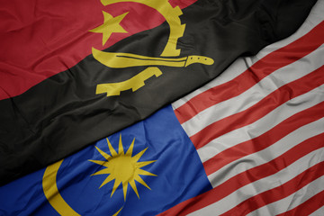 waving colorful flag of malaysia and national flag of angola.