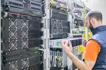 Technician repairs the central router in the datacenter server room. System administrator installs...