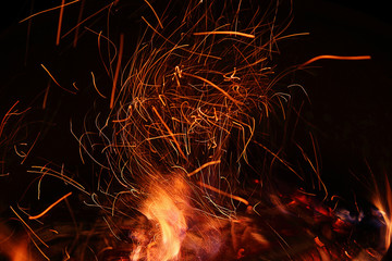 Fire, flame on a black background, burning coals and sparks from the fire, motion blur. Close-up. Abstract background.