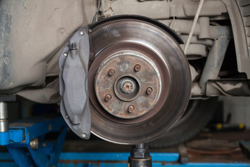 A close-up on the brake system of a car with pads, discs, a caliper on a lift in a vehicle repair...