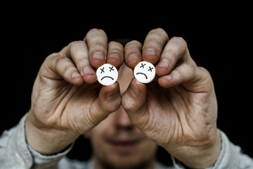 The man is holding two large white pills.  On tablets drawn emoticons.