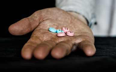 A man holding a multi-colored tablets.  On tablets drawn emoticons.