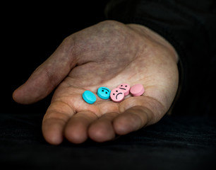 A man holding a multi-colored tablets.  On tablets drawn emoticons.