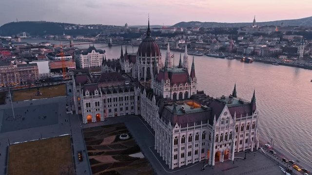 Fly around the top of the Parliament building in Budapest in the evening at sunset against the background of the Danube River, Secheni Chain Bridge