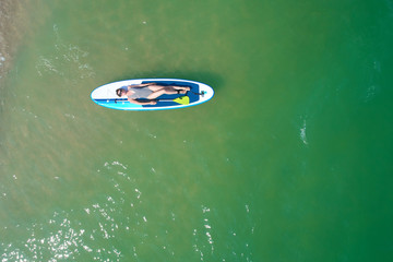 Fototapeta na wymiar Summer Vacations. Beautiful Young Woman Relaxing on the SUP at Turquoise Water. Beauty, Wellness. Recreation.