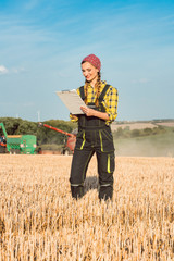Farmer on the wheat field doing bookkeeping on the ongoing harvest