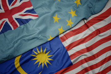waving colorful flag of malaysia and national flag of Tuvalu .
