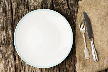 Table setting with vintage silverware or cutlery and empty plate on rustic wood. Top view.