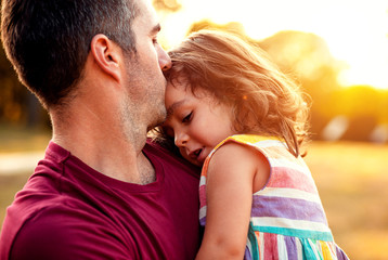Fototapeta premium Portrait of father holding daughter in his hands and hugging each other outdoors.