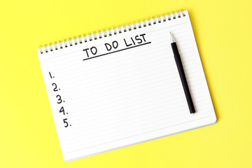 To Do List notepad and black pen on yellow background, copy space