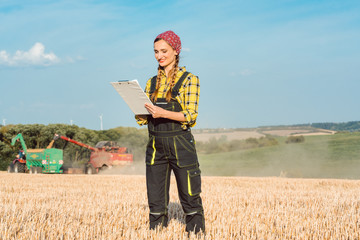 Farmer on the wheat field doing bookkeeping on the ongoing harvest