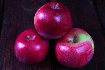 A few red ripe apples on an old dark wooden table