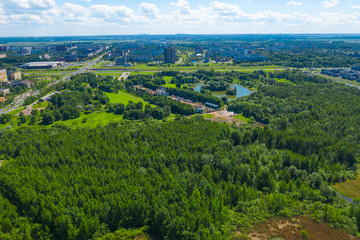 Fototapeta na wymiar Aerial view of south seaside park on southwest part of St. Petersburg city. Summer, a lot of green trees, blue sky, clouds. Russia