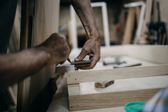 Close up shot of old master carpenter working in his woodwork or workshop. Traditional craftsmanship concept.