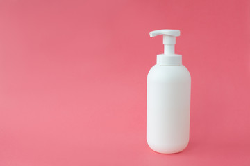 White cosmetic bottle on pink background