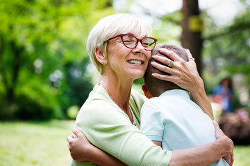 Happy grandma with grandson embracing in a park outdoors