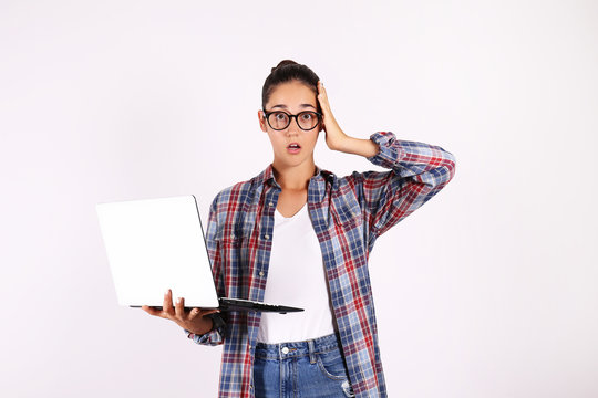 Young beautiful brunette woman with long black straight hair posing over bright colorful isolated background & holding laptop. Portrait of teenage female model showing emotions. Close up, copy space.