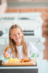 Adorable little girl having dinner at outdoor cafe