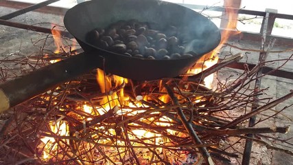 Chestnuts cooked with a traditional pan over fire, Italy