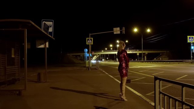 prostitute on side of road waiting for client at night. adult woman is engaged in prostitution.
