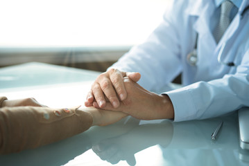 The doctor reassures the girl patient by putting his hands on top of the girl's hands