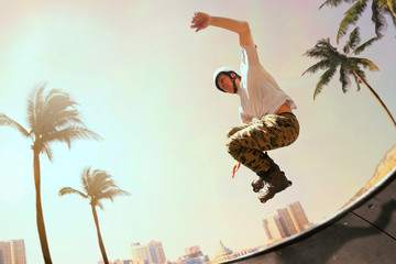 Rollerskater man is performing tricks in skatepark on sunset.