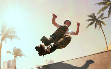 Rollerskater man is performing tricks in skatepark on sunset.