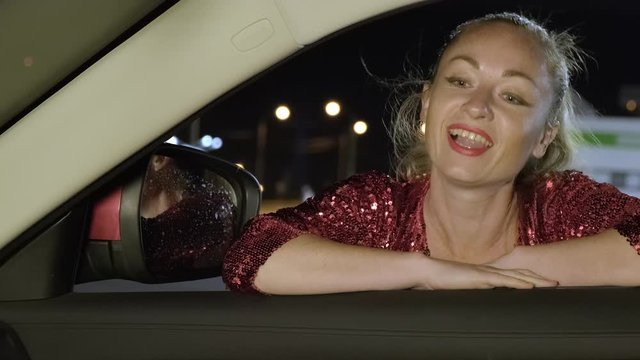 adult woman is engaged in prostitution at night. prostitute is talking to client through open car window.