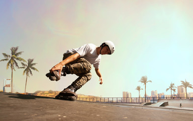 Rollerskater man is performing tricks in skatepark on sunset. © Artur Didyk