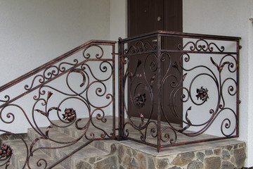 metal forged handrail to the house,metal railing on stairs of stone in the house and door