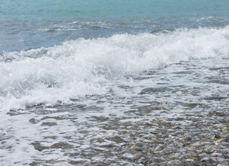 The wave rolls on the rocky shore.