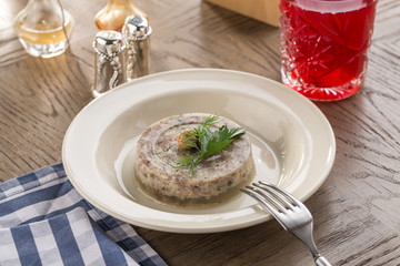 Holodets Homemade jellied meat with garlic and spices and glass of red drink on wooden table