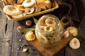 Mushroom preservation. Home preservation of products: glass jars with pickled mushrooms with spices on a rustic wooden table.