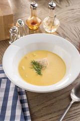 Pumpkin soup with meatballs on white plate and glass of red drink on wooden table