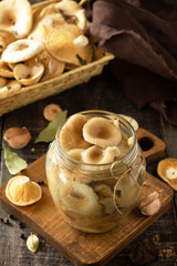 Mushroom preservation. Home preservation of products: glass jars with pickled mushrooms with spices on a rustic wooden table.