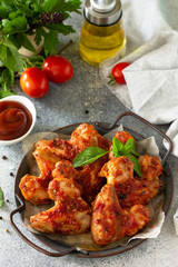 Tasty snack. Baked chicken wings with mustard tomato sauce on a concrete table.