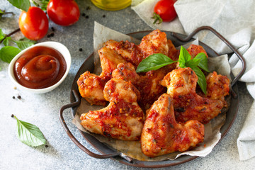 Tasty snack. Baked chicken wings with mustard tomato sauce on a concrete table.