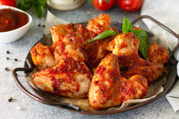 Tasty snack close-up. Baked chicken wings with mustard tomato sauce on a concrete table.