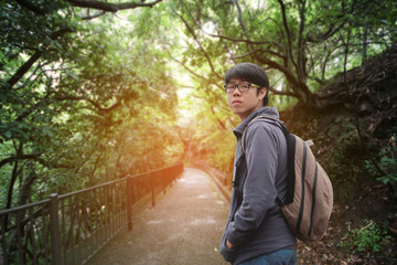 Male teenage tourist stand and looked back at the entrance to jungle.