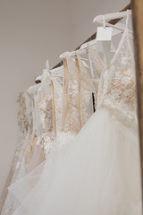 Assortment of dresses hanging on a hanger on the background studio. Fashion wedding trends. Interior of wedding shop